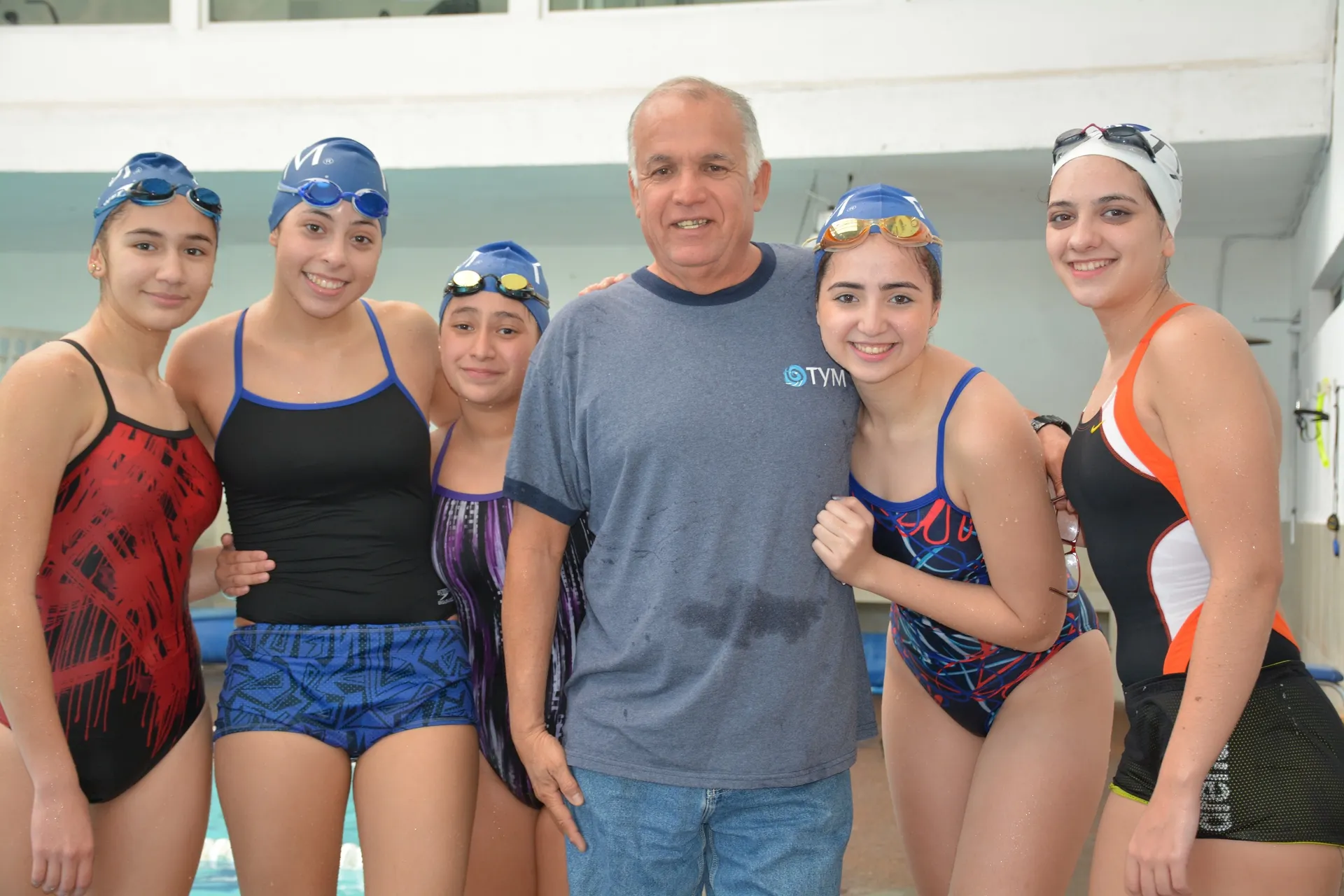 Coach Ernesto Hoyos con nadadoras de TYM en la alberca